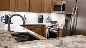 A modern kitchen with wooden cabinets, stainless steel appliances, and a marble countertop. - TRUE Ski-In Ski-Out Luxury 2 bd. 2 bth -Riverbend Lodge -Perfect location! (Breckenridge)