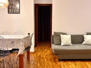 Un espace repas comprenant une table et des chaises, un canapé avec des coussins et un plancher en bois.