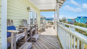 Une terrasse en bois avec des meubles d’extérieur, un espace abrité et une vue sur des maisons aux couleurs vives en arrière-plan.