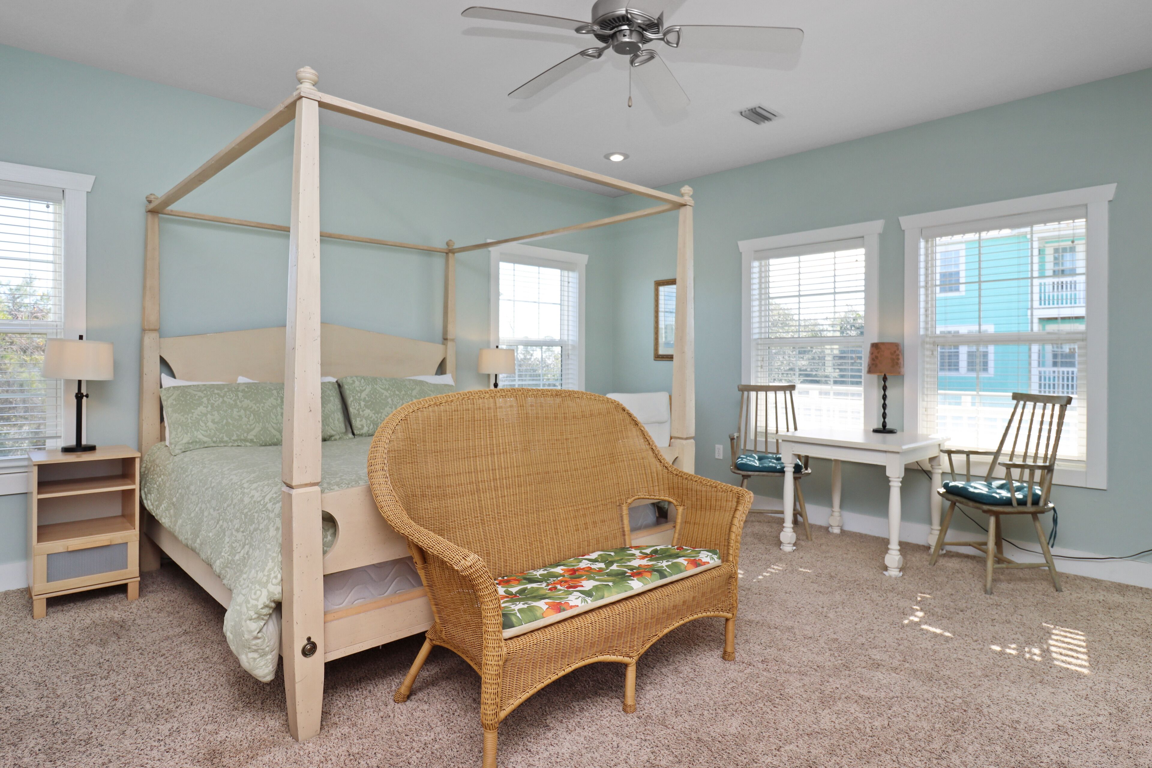 A four-poster canopy bed with a wooden frame and a green upholstered headboard.
