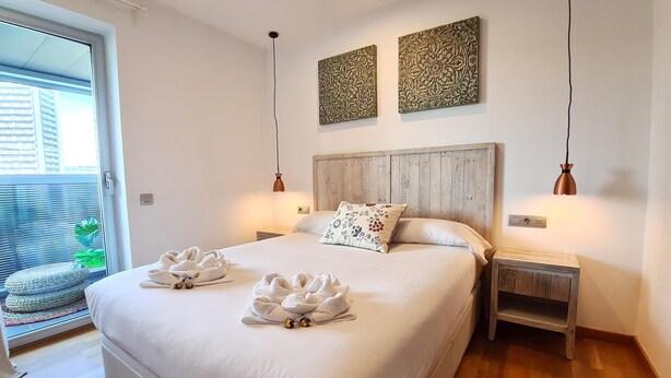 Une chambre à coucher moderne avec un grand lit, deux tables de chevet et une tête de lit en bois.