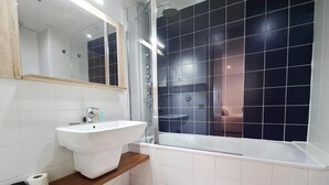 Une salle de bain moderne avec un lavabo blanc, un miroir, une cabine de douche et une baignoire.