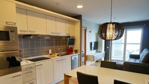 A modern kitchen with white cabinets, a built-in microwave, and a large island with chairs. - Apartment in Europe Square (Hospitalet de Llobregat)