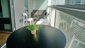 A balcony with a black table, two white chairs, and a small potted plant. - Apartment in Europe Square (Hospitalet de Llobregat)