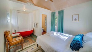 A bedroom with a bed, a chair, a red bathtub, and a ceiling fan. - Cabin #4 - The Perch at Twin Peaks (Twin Peaks)