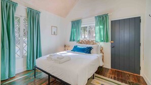 A bedroom with a bed, a door, and a window with curtains. - Cabin #4 - The Perch at Twin Peaks (Twin Peaks)