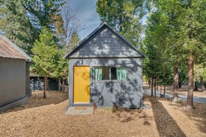 A small cabin with a yellow door, surrounded by trees.