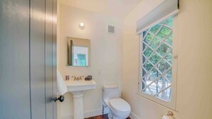 A bathroom with a pedestal sink, toilet, and a window with a view of trees. - Cabin #4 - The Perch at Twin Peaks (Twin Peaks)