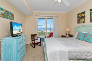 A bedroom with a bed, a dresser, a chair, a TV, a window with a view, and artwork on the walls. - Gulf View, Mexico Beach Condo, Community Pool, Hot Tub, and Sauna ~ Summerhouse (Mexico Beach)