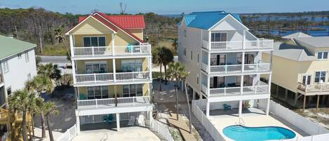 Un hotel frente a la playa con edificios de dos pisos, una piscina y vista al océano.