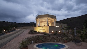Un bâtiment moderne doté d’une piscine, entouré d’un jardin aménagé et d’un mur en pierre.