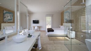 Une chambre moderne avec un grand lit, une douche à parois de verre, une coiffeuse blanche avec un lavabo en cuvette et un téléviseur à écran plat fixé au mur.