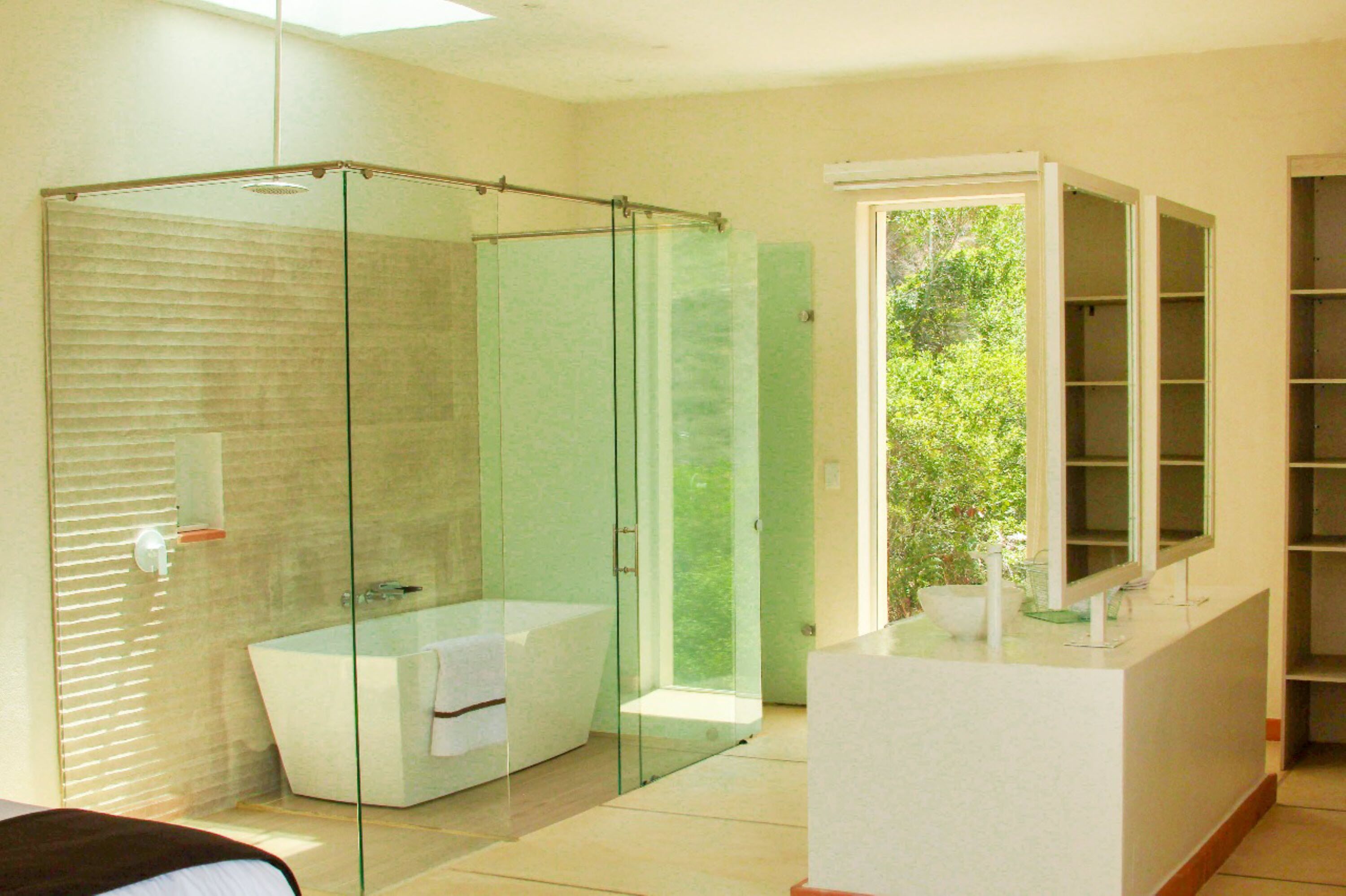 Un baño moderno con ducha de vidrio, bañera independiente y tocador con espejo.