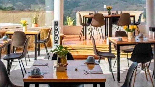 Un espace extérieur aménagé pour les repas, avec des tables et des chaises, de grandes fenêtres et une vue sur les montagnes.