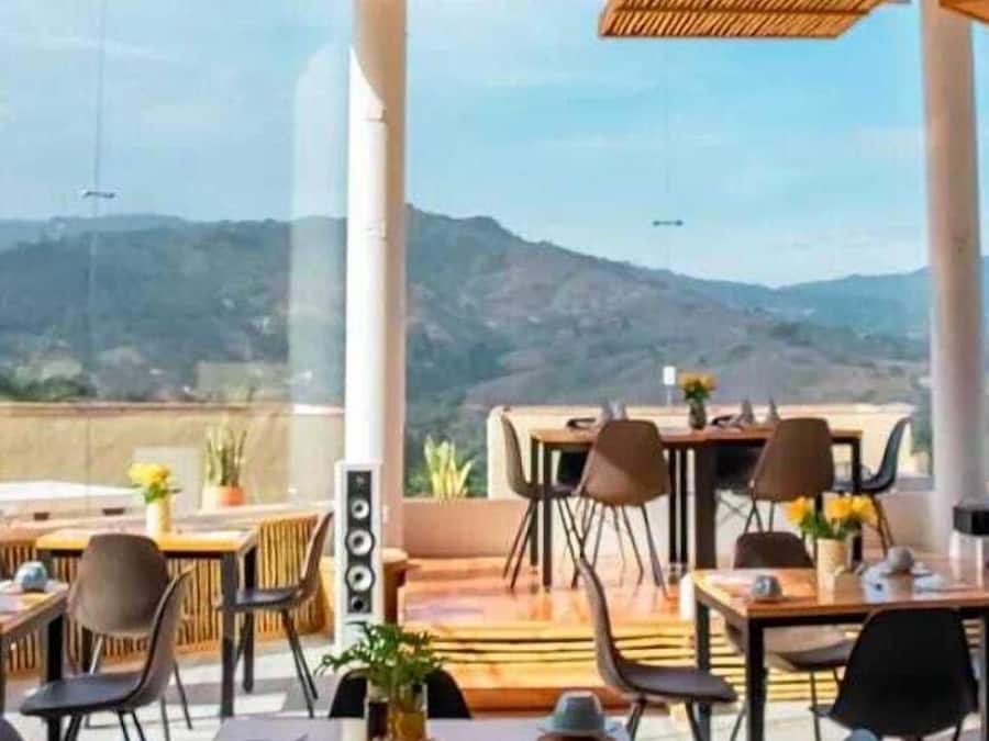 An outdoor dining area with tables and chairs, large windows, and a view of mountains.