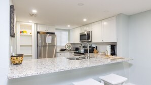 A modern kitchen with white cabinets, stainless steel appliances, and a granite countertop.
