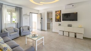 A modern living room with a sofa, a coffee table, and a TV mounted on the wall. - Jacaranda del Gastor by Ruralidays (Cádiz)