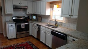 A kitchen with white cabinets, a stainless steel oven, a dishwasher, and a granite countertop. - Auburn Gameday Retreat (Opelika)