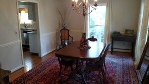 A dining room with a wooden table, chairs, a chandelier, and a patterned rug. - Auburn Gameday Retreat (Opelika)