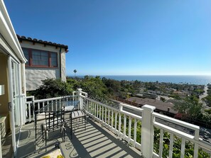 A balcony with a table and chairs, overlooking a residential area and the ocean. - Now booking Fall/Winter- Charming Beach View Cottage (Laguna Beach)