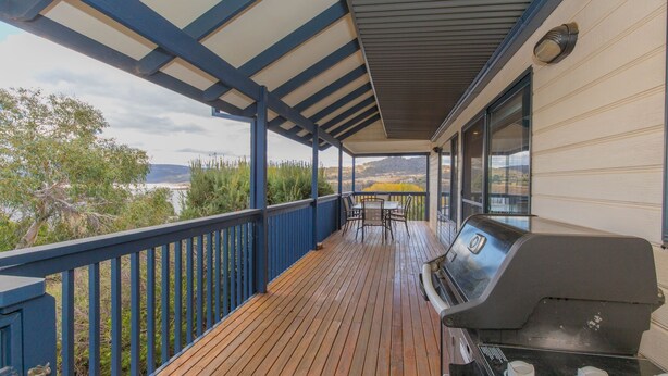 Una terraza techada al aire libre con una parrilla, una mesa y sillas.