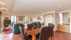 Amplia sala de estar con una mesa de comedor de madera, sillas de cuero y un sofá verde.