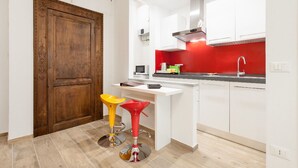 Eine moderne Küche mit weißen Schränken, einer roten Spritzschutzwand und zwei Barhocker.
