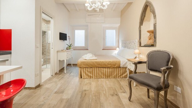 Ein Schlafzimmer mit Bett, Stuhl, Schreibtisch und Fernseher.