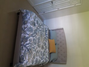 Cozy retreat with a bed, tufted headboard, and floral-patterned bedspread.