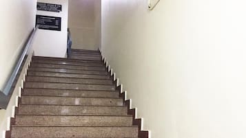 A staircase with a handrail, leading to a landing with a sign.