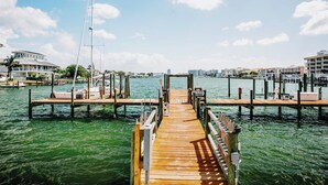 Un muelle de madera que conduce a un puerto deportivo con barcos y edificios al fondo.