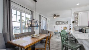 Un comedor espacioso con una mesa de madera, sillas y vistas a la ciudad a través de amplias ventanas.