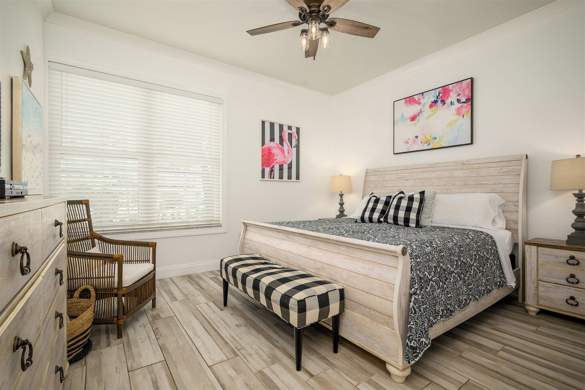 A bedroom with a bed, a chair, a bench, a dresser, a nightstand, and a ceiling fan.