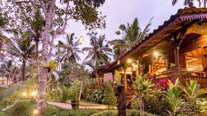 A tropical resort with a wooden structure, lush greenery, and palm trees. - Be Bali Hut Farm Stay (Ubud)