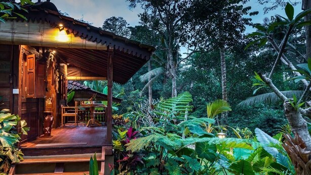 A wooden structure with a covered porch, surrounded by lush tropical vegetation. - Be Bali Hut Farm Stay (Ubud)