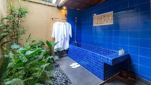A small bathroom with blue tiles, a shower, and a bench. - Be Bali Hut Farm Stay (Ubud)