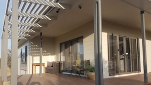 A wooden deck with outdoor furniture, a sliding glass door, and a modern architectural design. - Gilligan's Kangaroo Island (Baudin Beach)