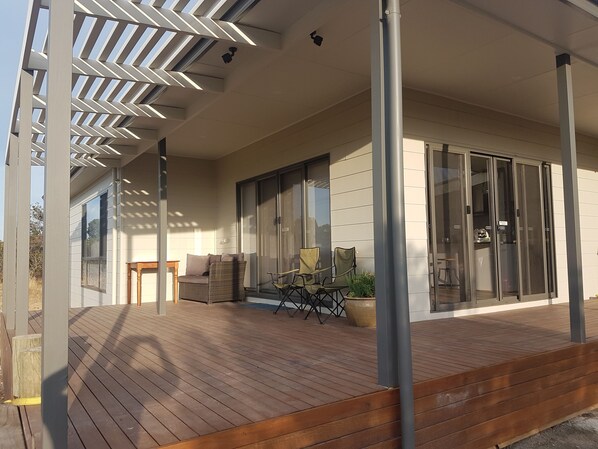 A wooden deck with outdoor furniture, a sliding glass door, and a modern architectural design.