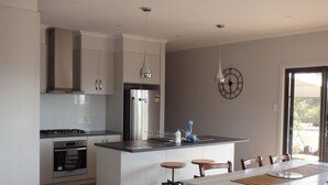 A modern kitchen with a central island, stainless steel appliances, and wooden flooring. - Gilligan's Kangaroo Island (Baudin Beach)