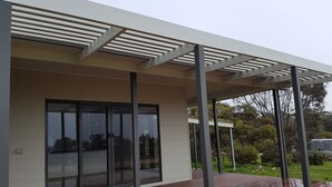 A modern building with a covered outdoor area, large glass windows, and a flat roof. - Gilligan's Kangaroo Island (Baudin Beach)