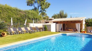 Ein Swimmingpool mit Liegestühlen und einer überdachten Sitzgruppe.
