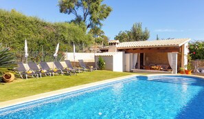 A swimming pool with lounge chairs and a covered seating area.