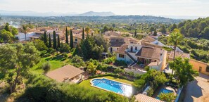 Une vaste villa dotée d’une piscine, entourée d’une végétation luxuriante et offrant une vue sur les montagnes lointaines.