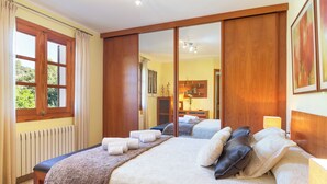Ein Schlafzimmer mit einem großen Bett, einem Holzschrank und Blick ins Bad.