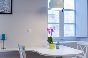 Un espace repas moderne avec une table blanche, une orchidée en pot et une lampe décorative.