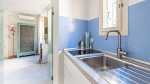 Una cocina moderna con un lavamanos grande, una ventana sobre el lavamanos y una puerta que da a otra habitación.