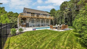 A two-story house with a covered patio, a swimming pool, and a well-maintained lawn.