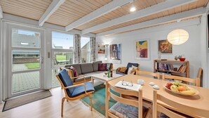 Ein modernes Wohnzimmer mit einer Couch, Sesseln, einem Esstisch und einem Bücherregal.