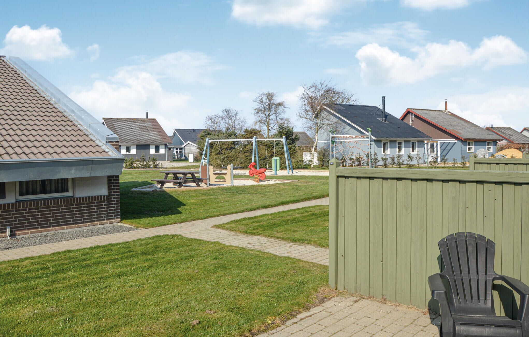 Een woonwijk met huizen, een speeltuin en een picknicktafel.