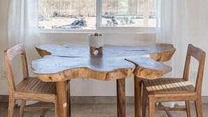 Een eetgedeelte met een houten tafel en stoelen, een raam met witte gordijnen en uitzicht op een besneeerd landschap.